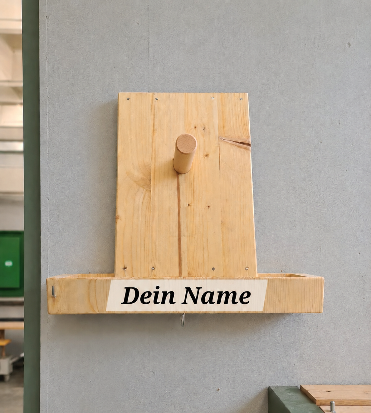 Handgefertigter Holz-Helmhalter mit personalisierter Gravur „Dein Name" an grauer Wand